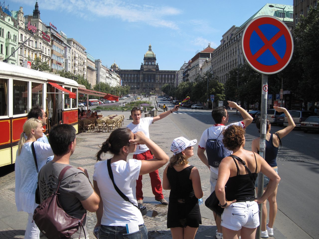 A tour guide speaking to tourists in a large square, with a magnificent monument in the background