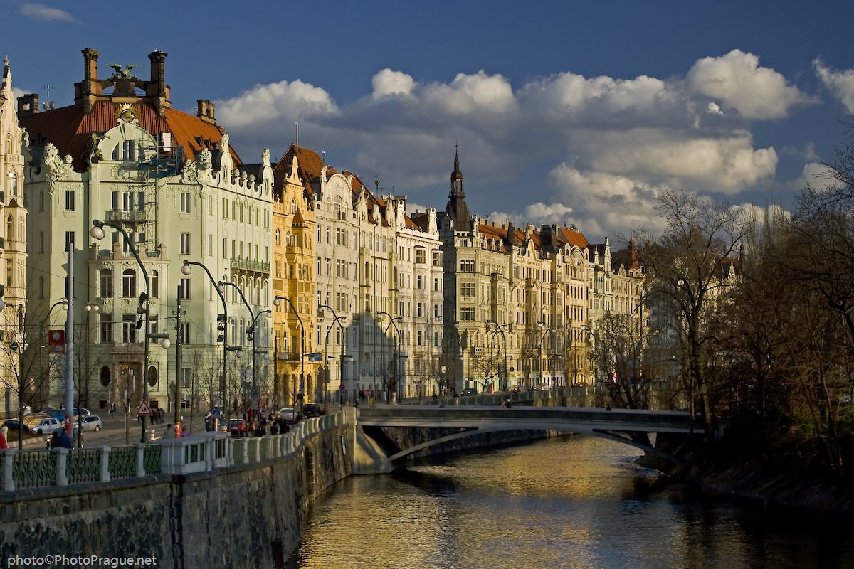 A row of colorful buildings along a calm canal spanned by a bridge