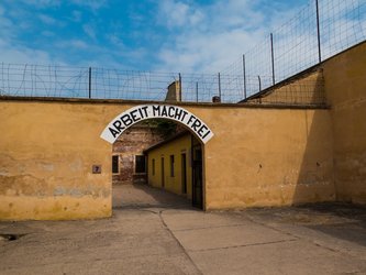 en:A weathered yellow wall, topped by an arched entrance bearing the inscription “Arbeit macht frei” ;fr:Un mur jaune abimé , surmonté d’une entrée en arche portant l’inscription « Arbeit macht frei