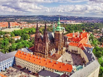 en:Aerial view of the Gothic cathedral at Prague Castle, surrounded by tall buildings with orange-colored roof tiles ;fr:Vue aérienne avec la cathédrale gothique du château de Prague, entourée de grands bâtiments aux tuiles oranges vif