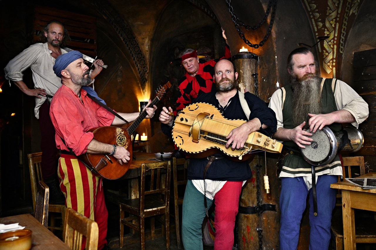 Five musicians in medieval costumes playing instruments