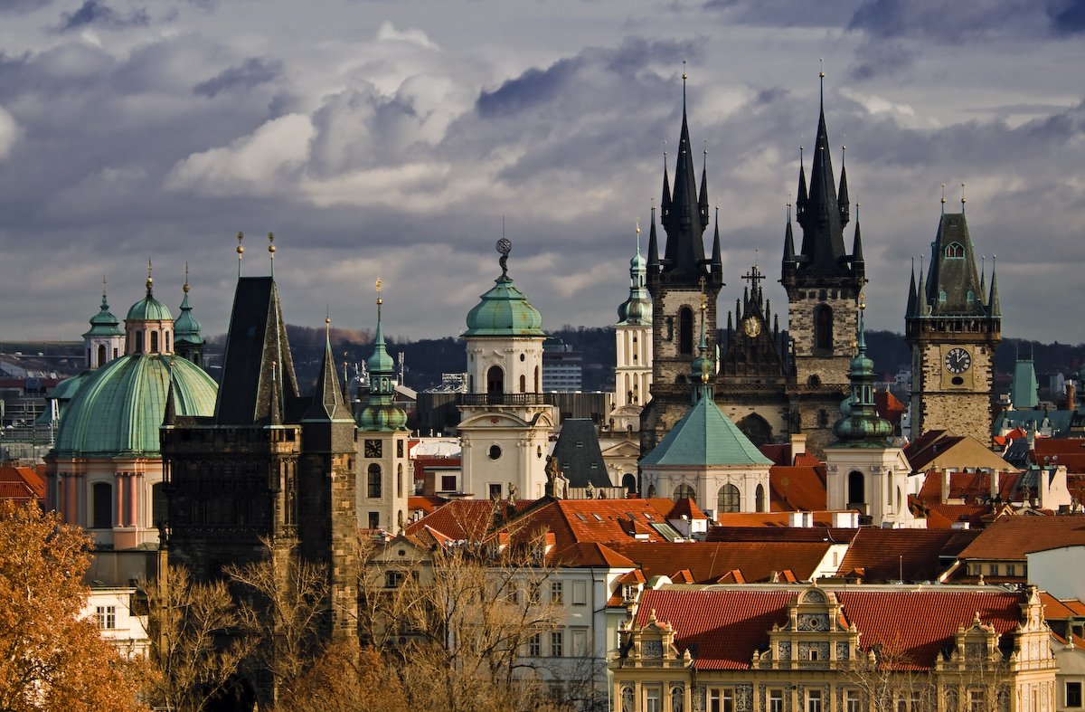 A panoramic view of the rooftops, with the Gothic spires of the church and the clock tower under a cloudy sky.